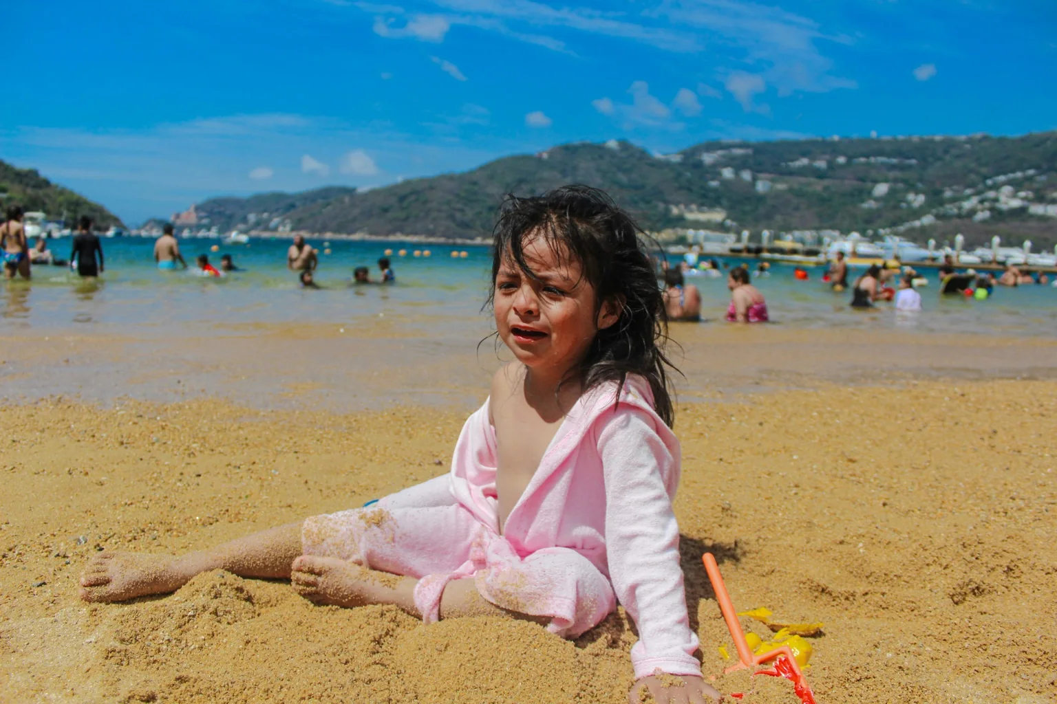 Niña jugando en la arena frente a una playa de Acapulco