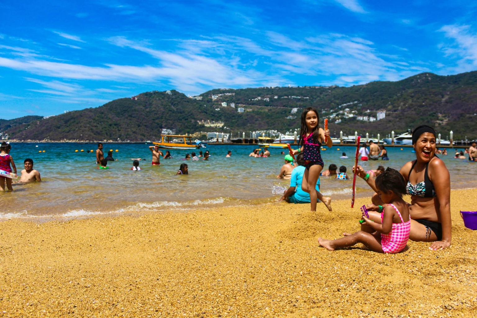Madre y niños jugando en la orilla de una playa de Acapulco