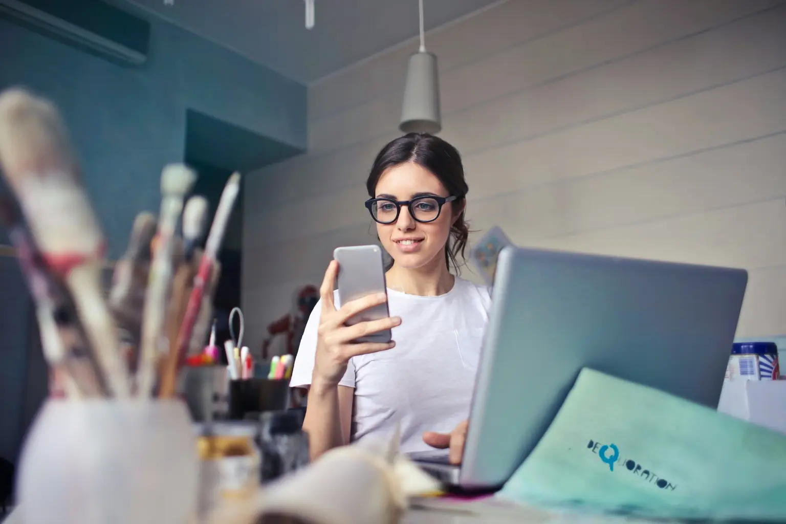 Persona trabajando desde casa con un portátil y un teléfono